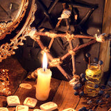Protection objects on a table with a pentagram, candles, and runes on a wooden surface.