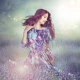 A beautiful woman in a floral dress standing amongst lavender flowers with sparkling light effects, representing Goddess Fortuna connections.