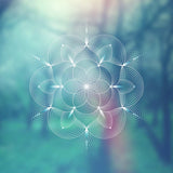 A glowing sacred geometry motif, against a soft blue-green background.