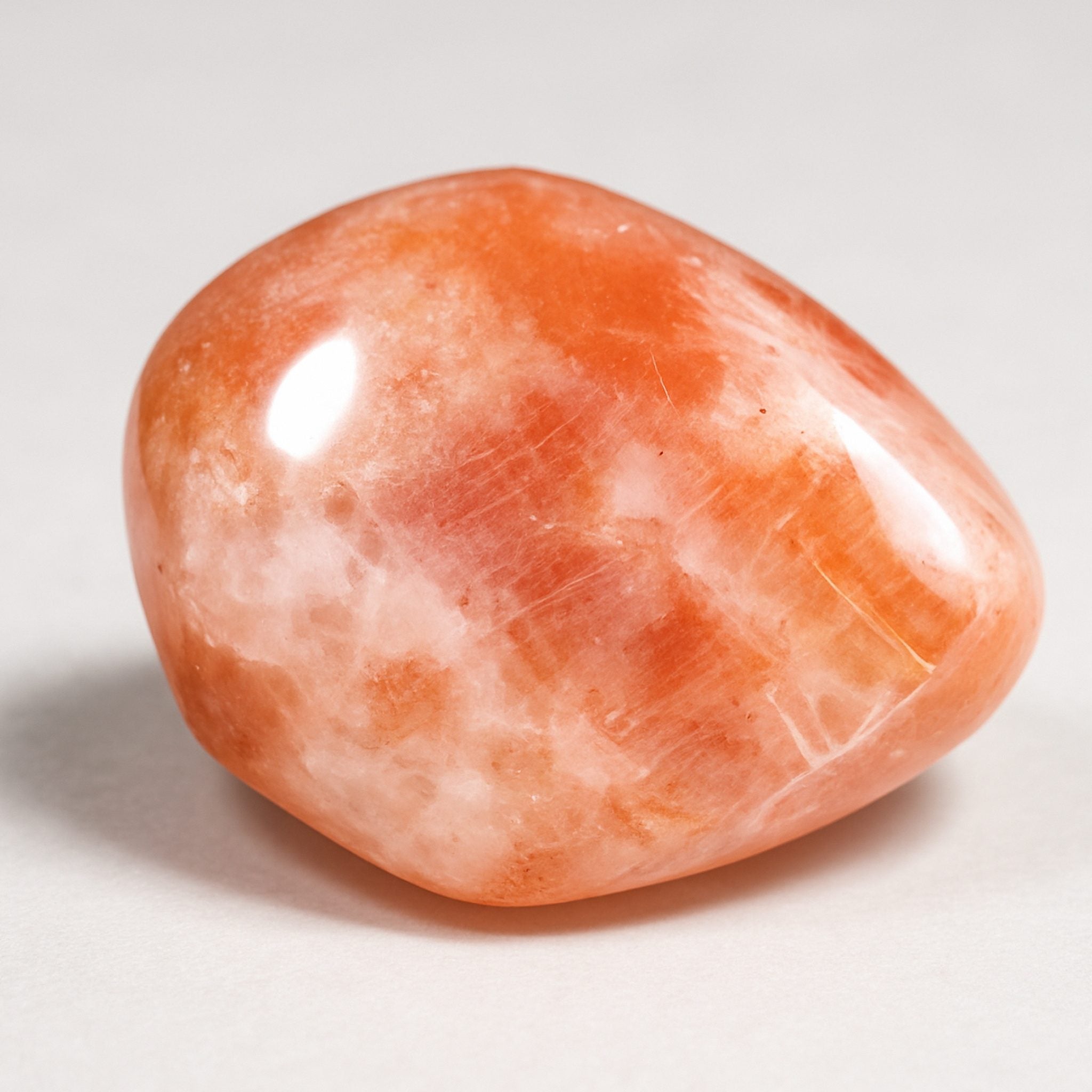A close-up of a polished orange and white Sunstone gemstone.