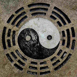 Yin and yang symbol on sand with八卦 (Bāguà) patterns symbolising Tao.