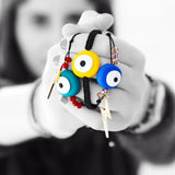 A person holding outstretched arms holding colourful evil eye charms on a white background.