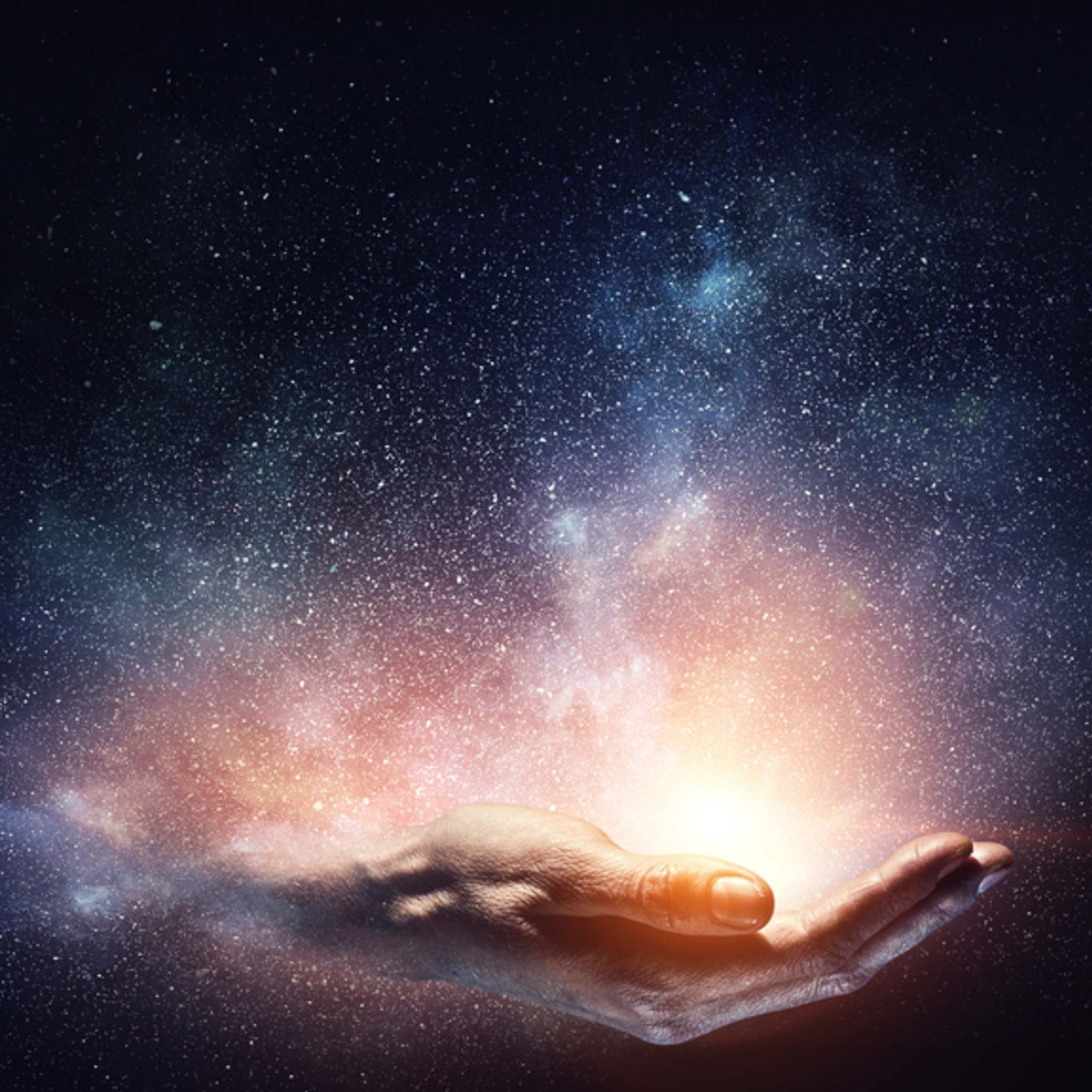 A photograph of a person's hand cupped and facing upwards, surrounded by a vivid orange and white glow, as if holding a small sun. The hand and light are set against a dark night sky filled with a dense pattern of white stars, representing high vibration and cosmic energy.