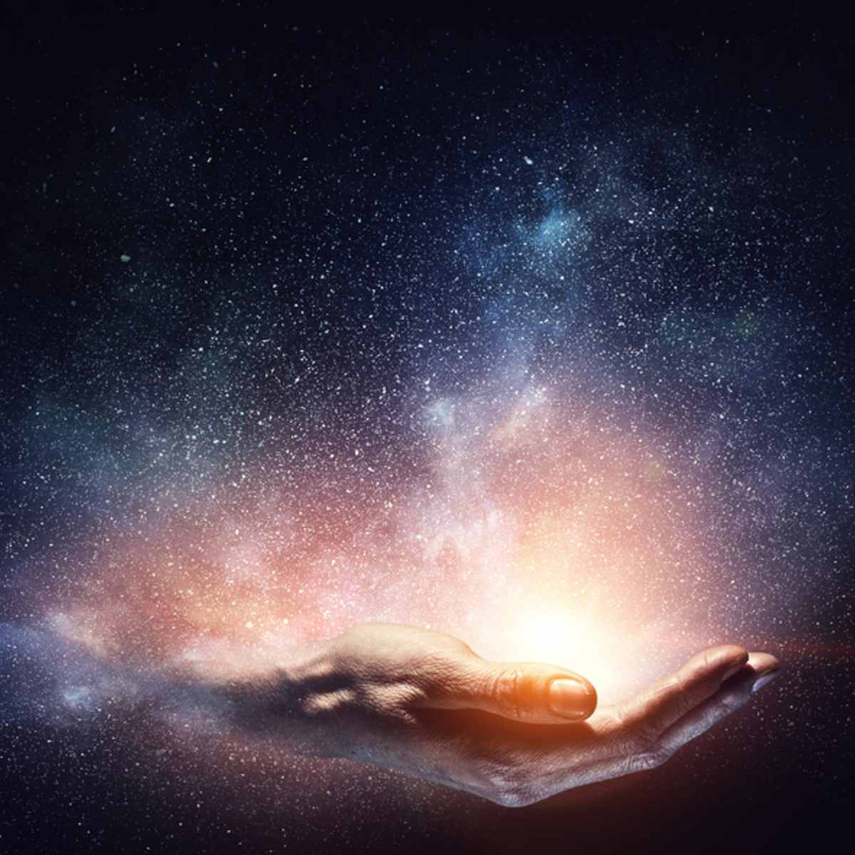 Hand holding a glowing orb with a starry night sky background representing high vibration energy.