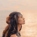 Side profile of a woman with braided dreadlocks looking upward against a soft, sunlit horizon, symbolising the inner shamanic warrior.