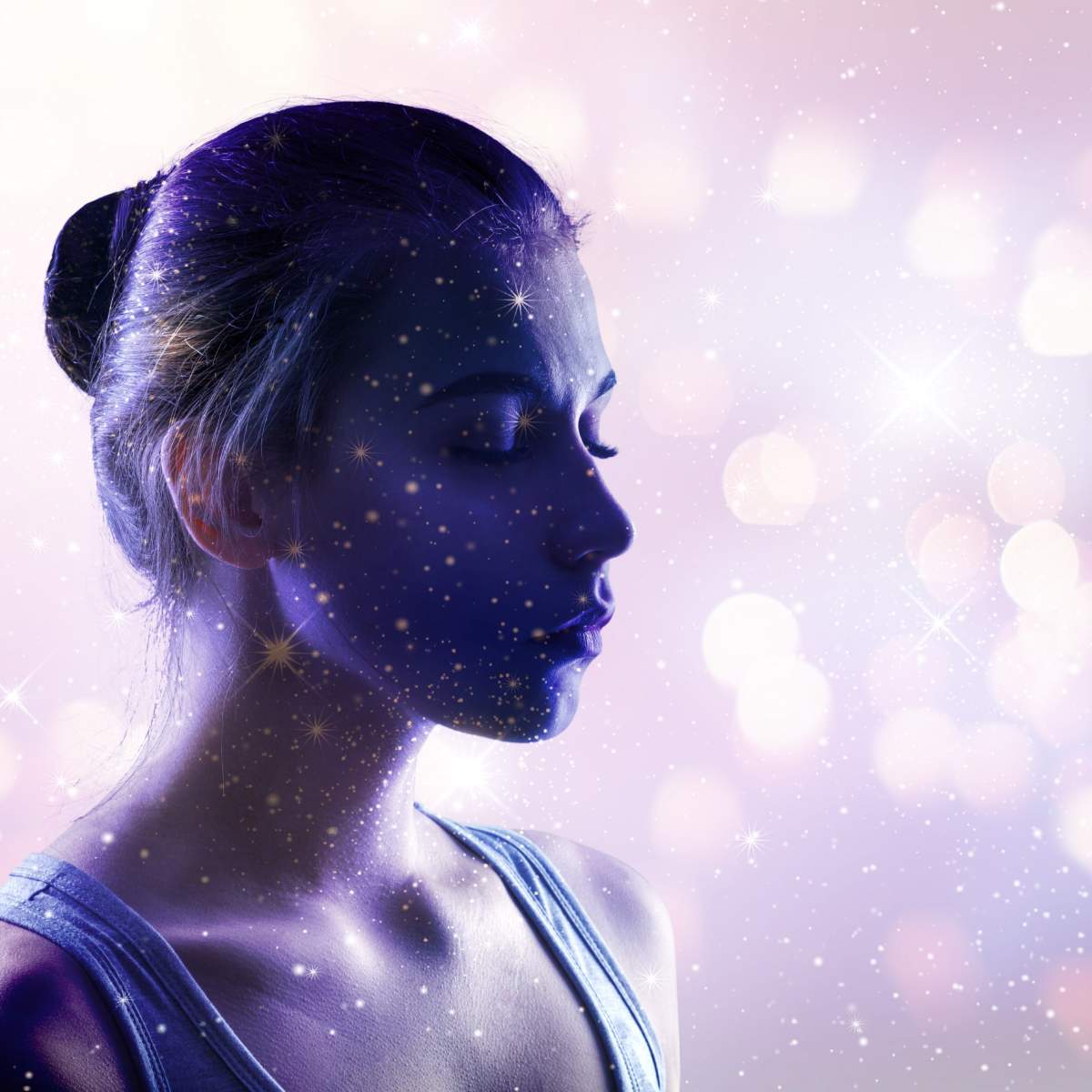 Woman with eyes closed and in deep meditation with beautiful pink sparkles against darker pink and light purple background.