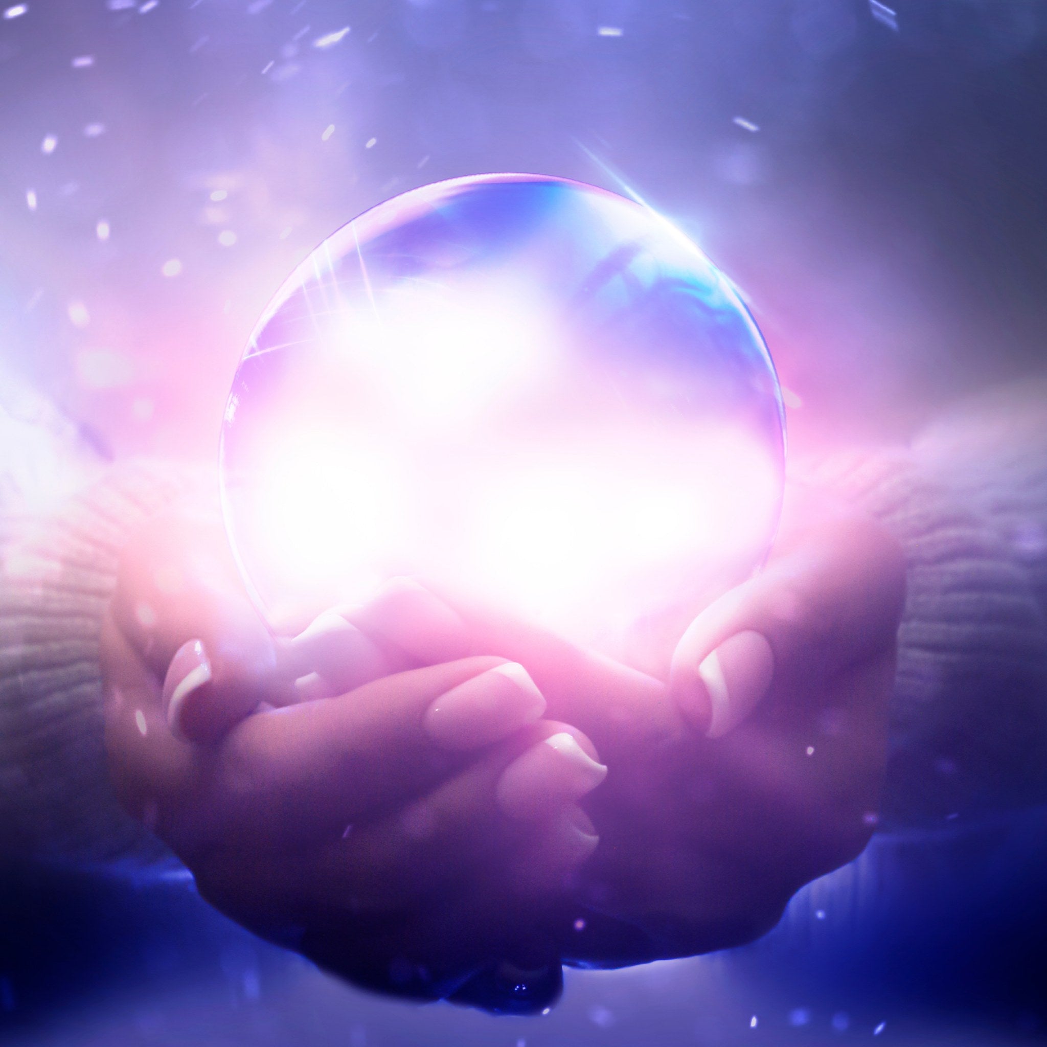 A pair of cupped hands holding a brilliant, glowing, iridescent sphere that resembles a crystal ball, radiating intense white and pink light. The background is dark with sparkling white dust or snow falling.