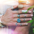 Hand wearing multiple decorative rings with a blurred natural background.