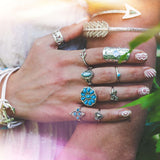 Hand wearing multiple decorative rings with a blurred natural background.