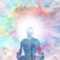 Silhouette of an enlightened person meditating against a colourful, radiant background.