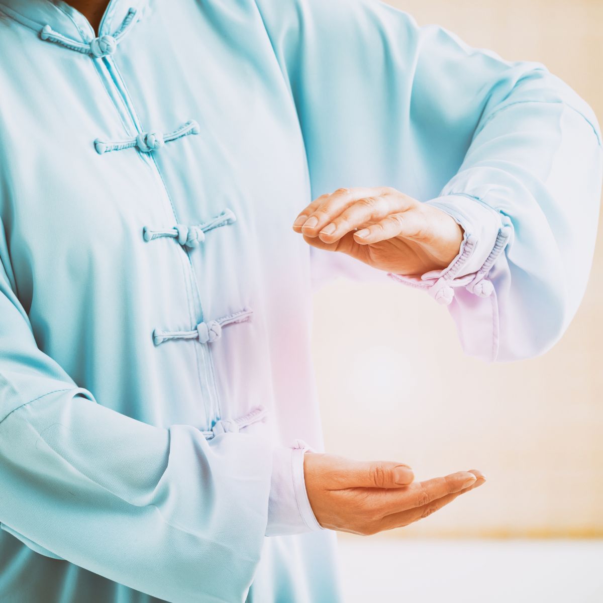 Woman in blue Chinese clothing holding her hands over an energy ball representing Qi Gong energies.