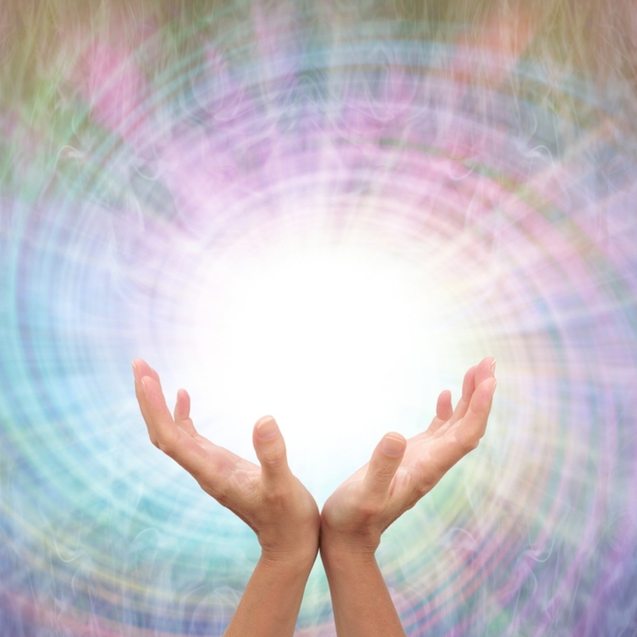 A close-up photograph of a pair of open hands cupped upwards, positioned to channel or receive energy. Above the hands is a brilliant white light emerging from a soft, swirling vortex pattern of multicoloured energy lines in pastel pink, green, and blue, symbolising the powerful Reiki connections.