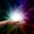 Hand holding a bright Reiki energy source with a colourful background.