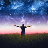 Person standing in a field with arms outstretched, facing a starry night sky.