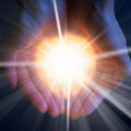 Hands cupping a bright light source with rays extending outward representing soul retrieval.