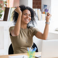 Woman with broad smile sitting at a desk in a bright office symbolising successful business.