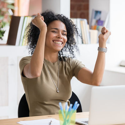 Woman with broad smile sitting at a desk in a bright office symbolising successful business.