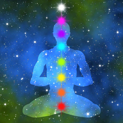 Silhouette of a person in meditation with chakra colours on a starry space background.