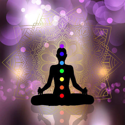 Silhouette of a person in meditation with chakra colours on a mandala background.