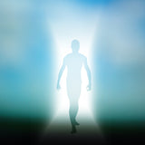 Silhouette of a man walking with white light shining from behind him representing an energetic doorway, with a spiritual blue background.