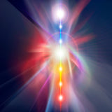 Abstract graphic of a central column of intense, multi-colored light extending vertically through a dark background, representing the activation and rising of Kundalini energy through the chakras.
