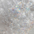 A macro close-up of a piece of clear quartz crystal, showing white shimmering rainbow iridescence, representing Causal Chakra clear quartz amplification.