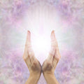 Hands held out against a soft, multicoloured background.
