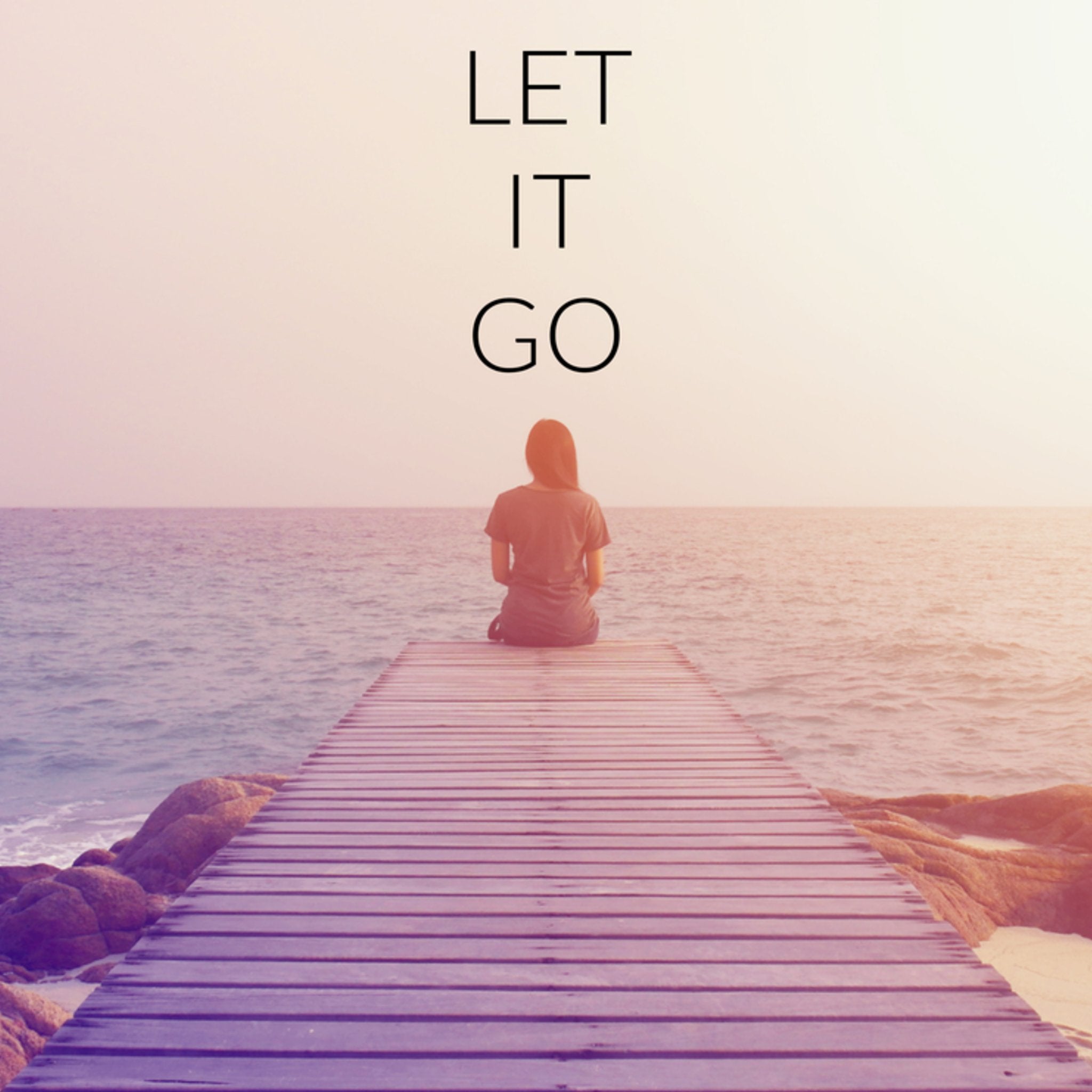 A person sits on a wooden pier, looking out at the calm ocean at sunset. The words "LET IT GO" are written in a simple font above them.