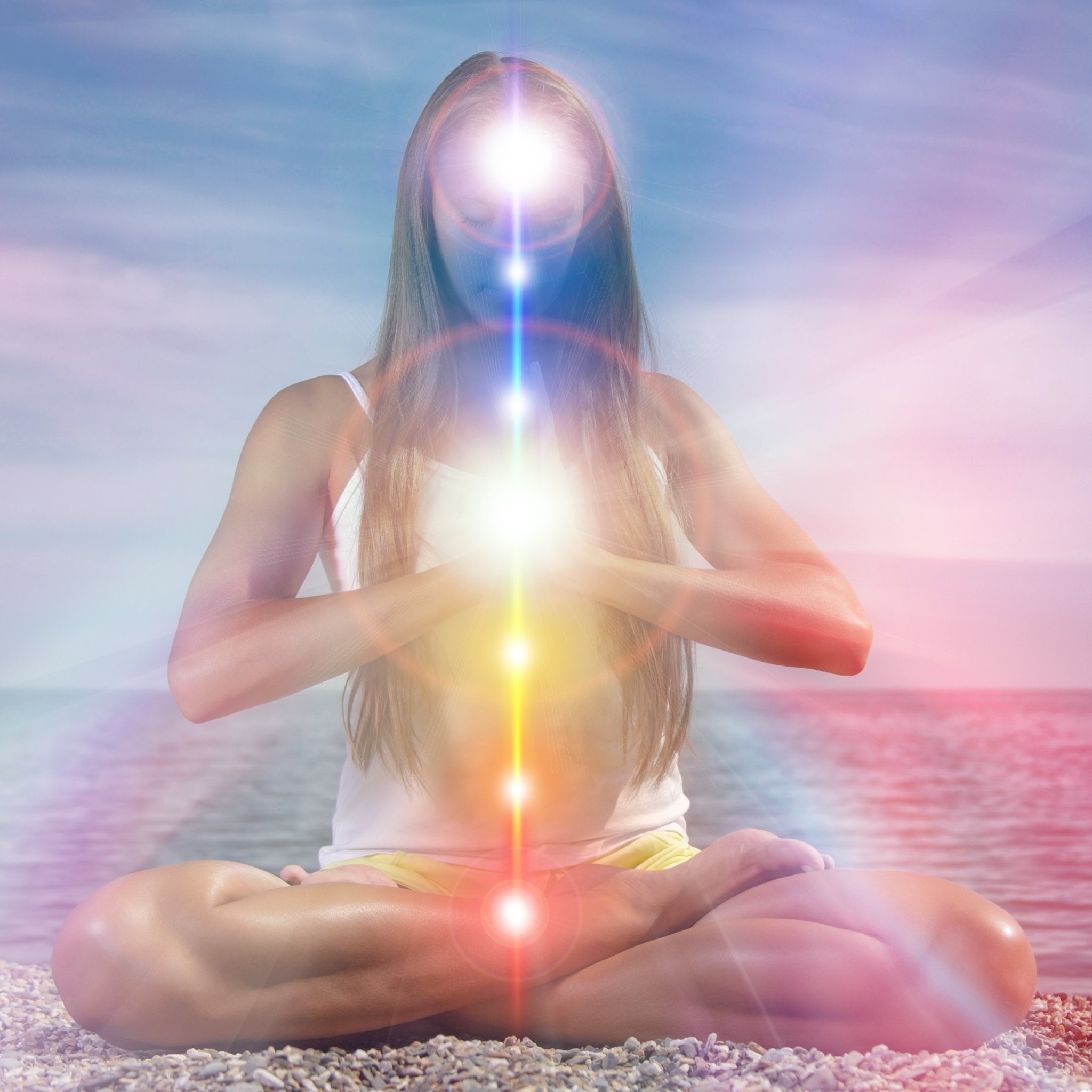 A woman meditating in the lotus position on a beach, with a vertical column of bright chakra lights running through her body, representing kundalini shakti integration.