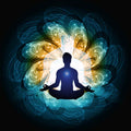 Silhouette of a person meditating with colourful life force energy waves on a dark background