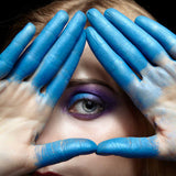 Close-up of an eye with hands painted blue forming a triangle, symbolising Third Eye activation.