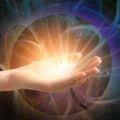 Hand holding a bright Reiki light source with a mystical background.