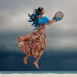 Woman in a colorful dress and headpiece floating against a cloudy sky.